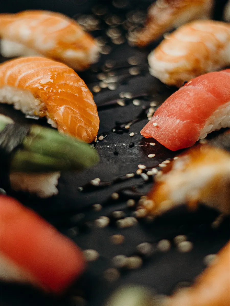 Close-Up of Salmon and Tuna Sushi with Sesame Seeds on Black Plate